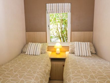 A bedroom with two single beds a bedside table with a lamp and a window at Willow Lodge in Troutbeck Bridge
