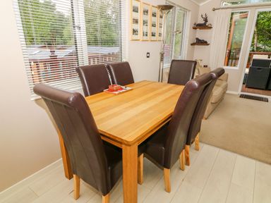 A dining room with a wooden table and six brown leather chairs at Willow Lodge in Troutbeck Bridge