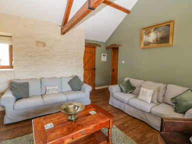 A living room with two sofas a wooden coffee table and framed painting on the wall at Beudy in Chwilog