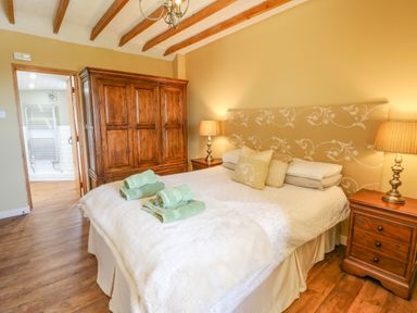 A bedroom with a bed towels wooden wardrobe bedside tables and lamps at Beudy in Chwilog