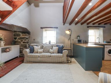 A living room with a sofa and kitchen area at Cegin Foch in Chwilog