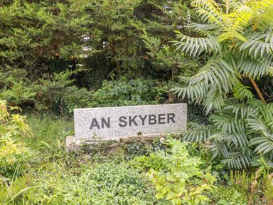 A stone sign engraved with an skyber surrounded by green bushes and plants at Cawsand Tideford