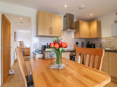 A kitchen with a wooden table and flowers in a vase at Cawsand, Tideford