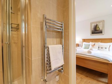 A bathroom with a shower and towel rail leading to a bedroom at Cawsand in Tideford