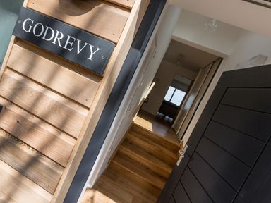 An open black door leading to a hallway with wooden floor and stairs at Godrevy in St Ives