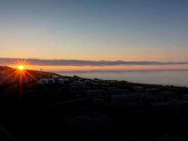 A sunset over a caravan park by the ocean at Godrevy in St Ives