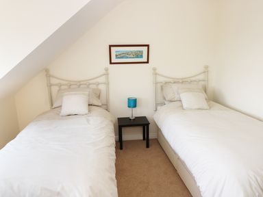 A bedroom with two single beds and a small table with a blue lamp at 5 Chandlers Yard in Burry Port