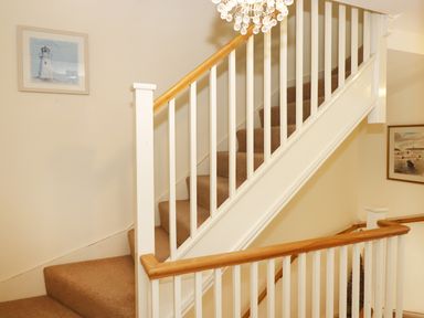 A staircase with beige carpet and white wooden railings with wooden handrails at 5 Chandlers Yard in Burry Port