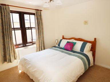 A bedroom with a double bed curtains on window and a bedside lamp at 5 Chandlers Yard in Burry Port