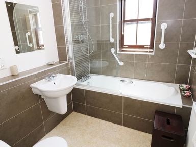 A bathroom with a sink and bathtub with shower at 5 Chandlers Yard in Burry Port