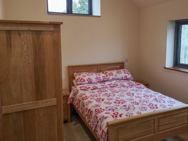 A bedroom with a wooden bed and wardrobe and floral bedding at The Milking Barn in Yeovil Somerset