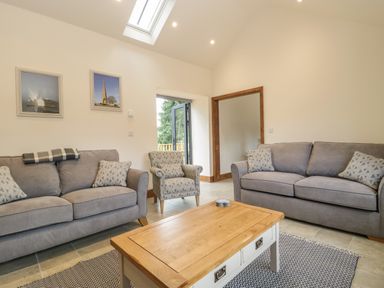 A living room with two gray sofas an armchair and a wooden coffee table at The Milking Barn in Yeovil Somerset