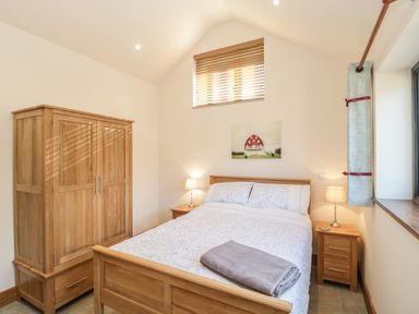 A bedroom with a double bed bedside tables lamps and a wardrobe at The Milking Barn in Yeovil Somerset