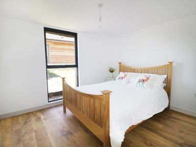 A bedroom with wooden bed frame white bedding two pillows with deer prints and a window at Heron Lodge Castle Farm in Wedmore