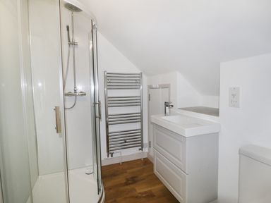 A bathroom with a corner shower enclosure a white sink with cabinet and a towel radiator at Heron Lodge Castle Farm Wedmore