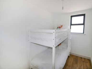 A bedroom with a white bunk bed and pillows with deer designs at Heron Lodge Castle Farm in Wedmore