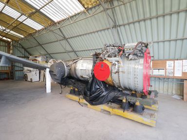 An aircraft engine on a yellow support structure inside a metal hangar at Heron Lodge Castle Farm in Wedmore