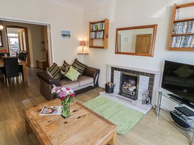 A living room with a sofa table with flowers and a fireplace with a television at Chwech in Menai Bridge