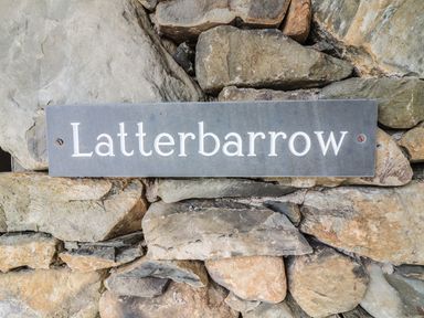 A rectangular sign with the word Latterbarrow mounted on a stone wall at Latterbarrow in Hawkshead