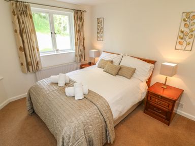 A bedroom with a double bed side tables lamps and a window with curtains at Latterbarrow in Hawkshead