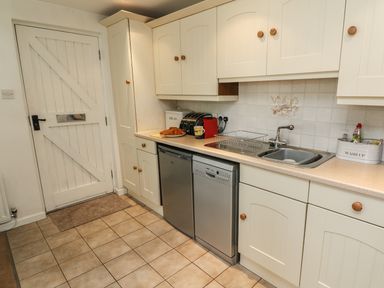 A kitchen with white cabinets stainless steel dishwasher and small fridge at Latterbarrow in Hawkshead