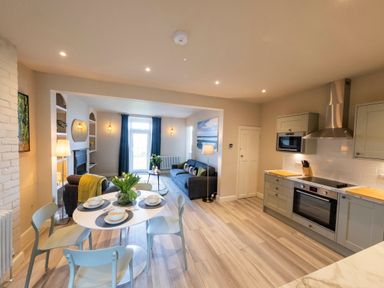 An open plan kitchen and living area with a dining table set with dishes and flowers at Harbour View Cottage in Watchet