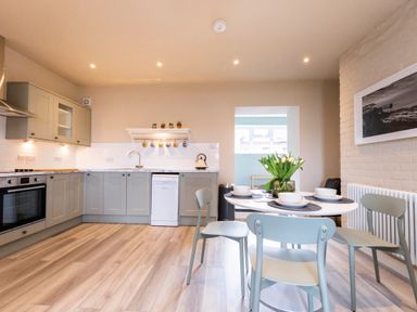 A kitchen and dining area with a round table set for four and gray cabinets at Harbour View Cottage in Watchet