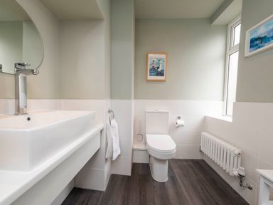 A bathroom with a sink mirror toilet towel radiator and two framed pictures at Harbour View Cottage in Watchet