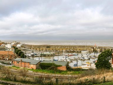 A small harbor with boats docked and houses nearby by the sea at Harbour View Cottage in Watchet