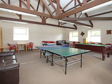 A game room with a ping pong table a pool table a foosball table chairs and sofas at Running Waters in Callington