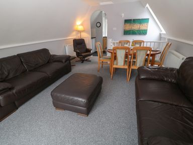 A living room with leather sofas a dining table and chairs and a lamp at Running Waters in Callington