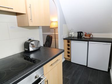 A kitchen with two mini fridges a toaster an electric kettle cups on a rack and a basket with packets at Running Waters in Callington