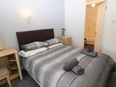 A bedroom with a double bed with gray bedding and rolled towels at Running Waters in Callington