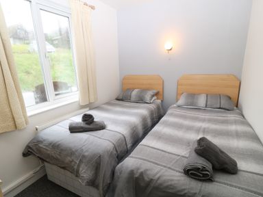 A bedroom with two single beds with grey bedding and towels on them at Running Waters in Callington