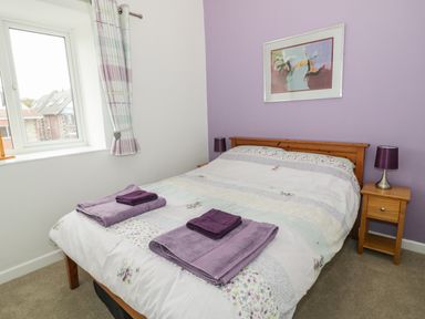 A bedroom with a double bed two bedside tables lamps and a wall painting at Swanage Bay Apartment in Swanage