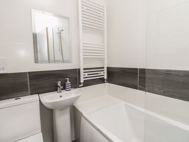 A bathroom with a toilet sink towel radiator bathtub and mirror at Swanage Bay Apartment in Swanage