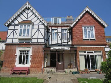 A brick and timber house with two gables and a central entrance labeled The Gables in Swanage