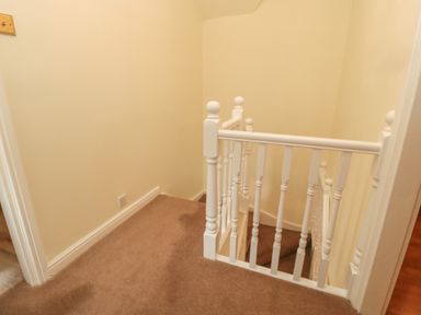 A stair landing area with beige carpet and white banisters at Red Squirrel Cottage 5 Biddlestone in Rothbury