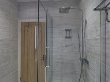 A bathroom with a glass shower enclosure and a wooden door at Flat 3 Peacehaven Sandsend near Whitby
