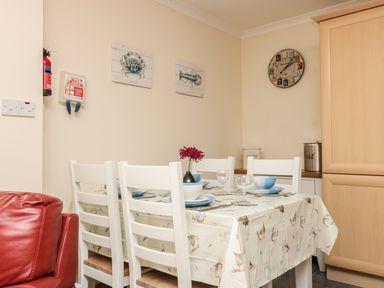 A dining area with a table set for four and white chairs at Sorrel Cottage in Padstow