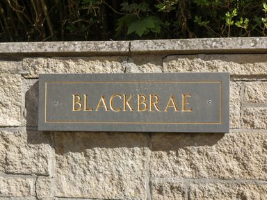 A stone wall with a plaque that reads Blackbrae at Blackbrae Cabin in Glenboig near Coatbridge Glasgow and Stirling