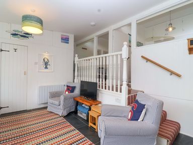 A living room with armchairs and a television at 2 Brook Cottages Hope Cove