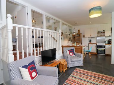 A living room with a TV and kitchen unit at 2 Brook Cottages in Hope Cove