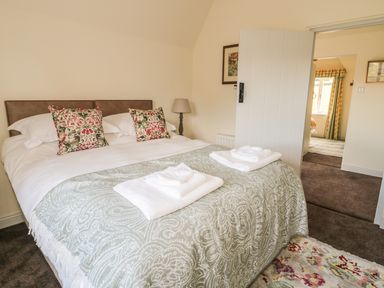 A bedroom with a bed with decorative pillows towels and a lamp next to the bed at Newbiggin Cottage in Blanchland