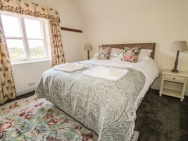 A bedroom with a double bed with patterned pillows and a throw at Newbiggin Cottage in Blanchland