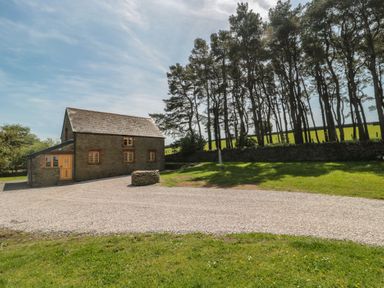 A house with a gravel driveway and trees at Penrhiwarwydd Barn Pontywaun