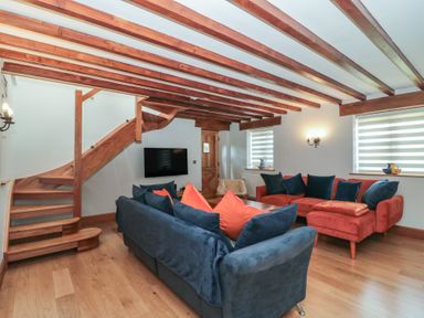 A living room with a staircase and sofa at Penrhiwarwydd Barn Pontywaun