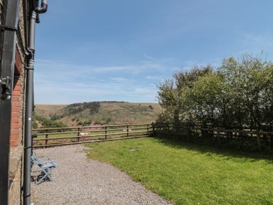 A garden with a fence and hill view at Penrhiwarwydd Barn Pontywaun