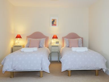 A bedroom with two single beds with red checkered headboards and red lamps on bedside tables at Carpenters Cottage in Cockermouth