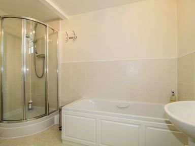 A bathroom with a shower enclosure a bathtub and a sink at Carpenters Cottage in Cockermouth
